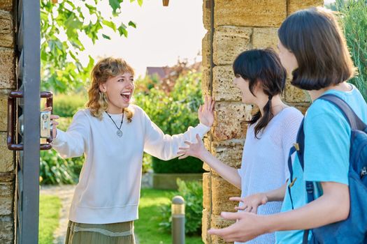 Meeting of friends, a young female with a guy and a girl near the front door to the yard. Welcome, youth, friendship, students, lifestyle concept