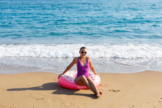 Woman on vacation on the beach relaxing in an inflatable ring on the ocean beach in travel. Girl in a swimsuit on the seashore in Turkey