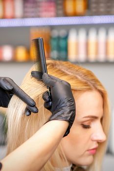 Beautiful young blonde woman with long straight blonde hair getting a haircut at the hairdresser salon