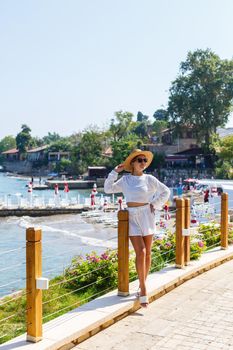 A young slender tanned woman in white shorts and a T-shirt, wearing sunglasses and a hat. Walk on a hot sunny day in the ancient city
