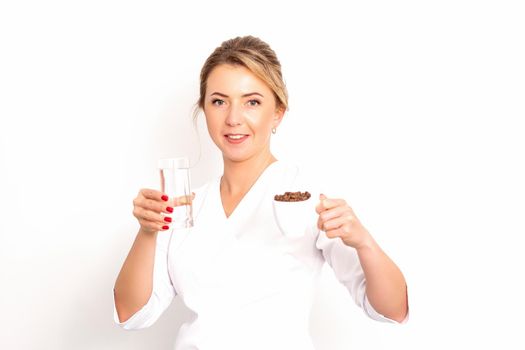Coffee with water. The female nutritionist holds a cup of coffee beans and a glass of water in her hands on white background