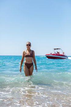 Beautiful woman in a swimsuit and walks on the sand on the beach in Turkey. Holidays in turkey. Photographed with the sea and waves in the background. Selective focus