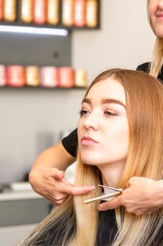 Beautiful young blonde woman with long straight blonde hair getting a haircut at the hairdresser salon