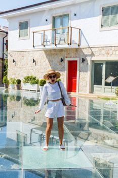 A young slender tanned woman in white shorts and a T-shirt, wearing sunglasses and a hat. Walk on a hot sunny day in the ancient city