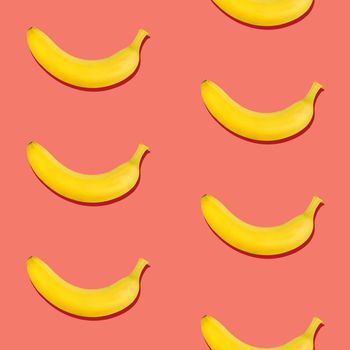 Seamless pattern of fresh ripe yellow bananas on coral pink background