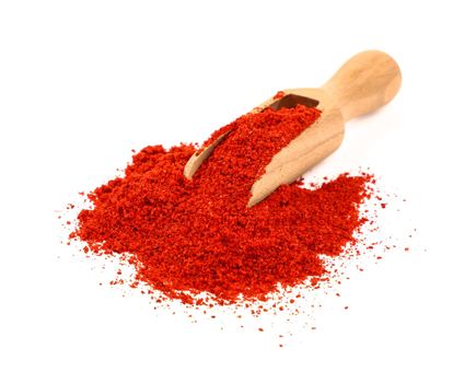 Close up one wooden scoop full of red chili pepper, paprika or sundried tomato powder spilled and spread around isolated on white background, high angle view