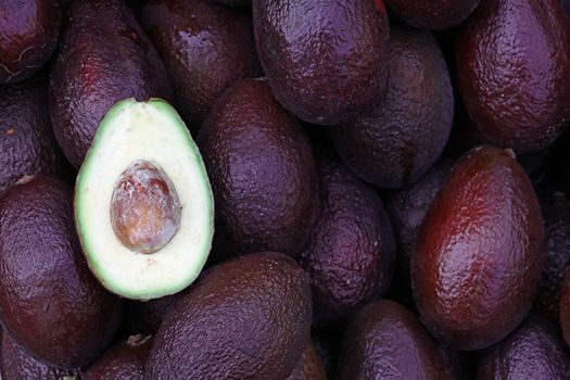 Close up many fresh ripe ready to eat purple avocado at retail display of farmer market, high angle view