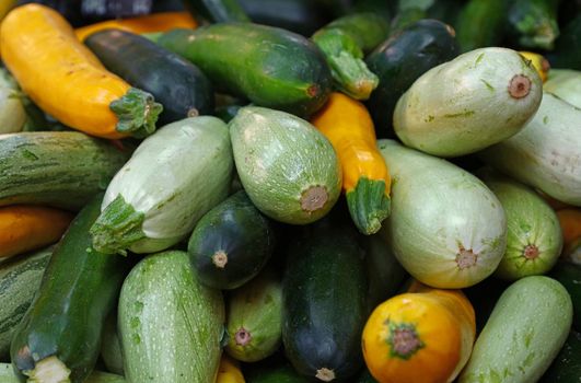 Close up fresh new green and yellow zucchini on retail display of farmers market, high angle view