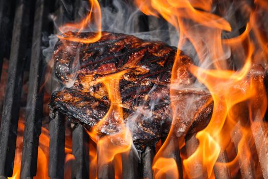 Close up searing and smoking ribeye beef steaks on open fire outdoor grill with cast iron metal grate, high angle view