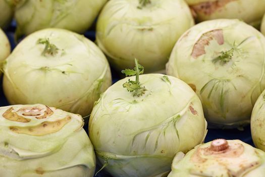 Close up many fresh green kohlrabi cabbages (German turnip) at retail display of farmer market, high angle view