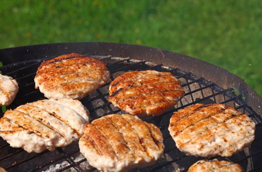 Close up chicken or turkey poultry meat barbecue burgers for hamburgers prepared on bbq grill, high angle view