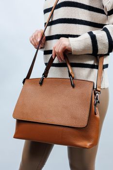 Woman with brown leather bag isolated on white background. Stylish clutch bag. Close-up vertical photo.