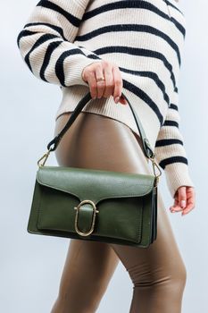 Small green leather bag in a female hand on a white background. Shoulder bag. A woman with a green handbag. Style, fashion, vintage and elegance.