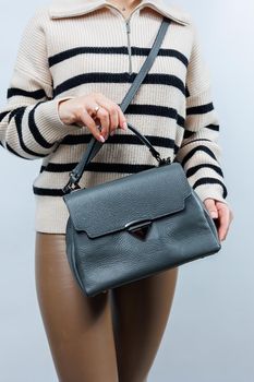 Woman with a gray leather bag on a white background. Stylish clutch bag. Close-up vertical photo.