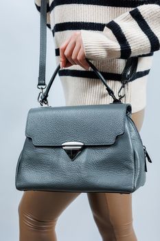 Woman with a gray leather bag on a white background. Stylish clutch bag. Close-up vertical photo.