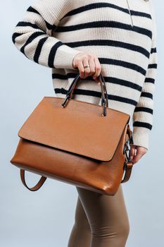 Woman with brown leather bag isolated on white background. Stylish clutch bag. Close-up vertical photo.
