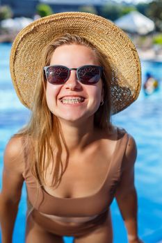 Slender woman model in a swimsuit posing near the pool. Summer vacation at the hotel,