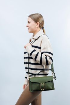 Small green leather bag in a female hand on a white background. Shoulder bag. A woman with a green handbag. Style, fashion, vintage and elegance.