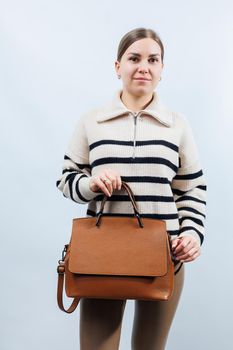 Woman with brown leather bag isolated on white background. Stylish clutch bag. Close-up vertical photo.