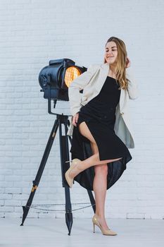Beautiful young female legs in beige high-heeled shoes, a black long dress and a beige jacket. Open autumn and spring outfit with heeled shoes