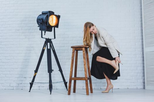 A woman is holding her leg she is wearing high heeled shoes and her legs hurt. The woman is wearing a black dress and beige high heel shoes. Leg pain from high heels