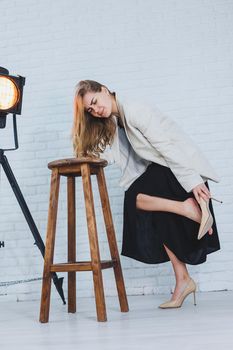 Young woman with pain in her legs after wearing high heels, close up. A woman in a black dress and jacket.