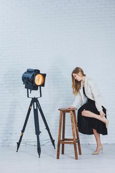 A woman is holding her leg she is wearing high heeled shoes and her legs hurt. The woman is wearing a black dress and beige high heel shoes. Leg pain from high heels