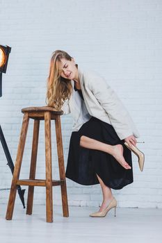 A woman is holding her leg she is wearing high heeled shoes and her legs hurt. The woman is wearing a black dress and beige high heel shoes. Leg pain from high heels