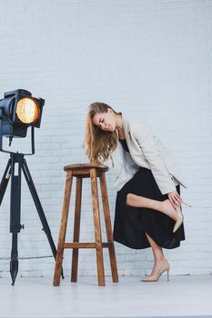 A woman is holding her leg she is wearing high heeled shoes and her legs hurt. The woman is wearing a black dress and beige high heel shoes. Leg pain from high heels