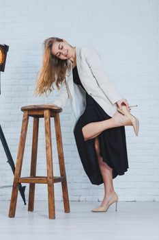 A woman is holding her leg she is wearing high heeled shoes and her legs hurt. The woman is wearing a black dress and beige high heel shoes. Leg pain from high heels