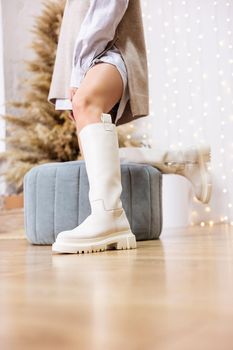 Trendy beige trumpet boots on a female leg, close-up, fashionable. New collection of women's shoes with genuine leather