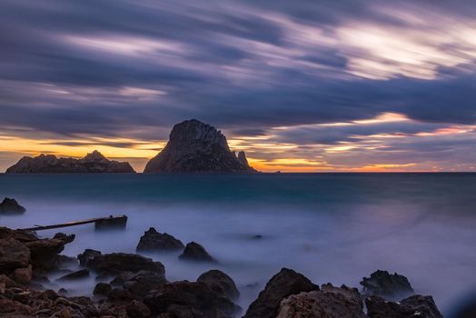 Small wooden pier in Cala d'Hort bay and view of Es Vedra island, Ibiza island, Spain