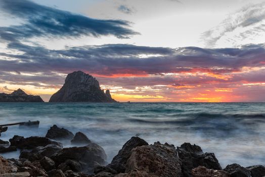 Small wooden pier in Cala d'Hort bay and view of Es Vedra island, Ibiza island, Spain