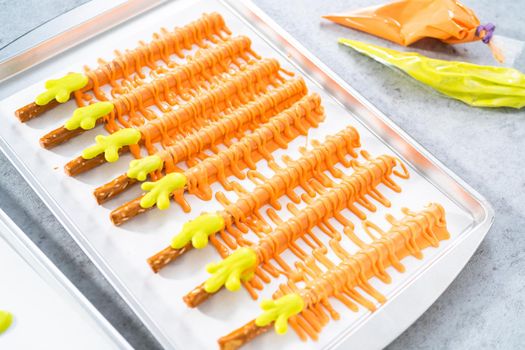 Dipped in chocolate pretzel rods on a baking sheet with parchment paper.