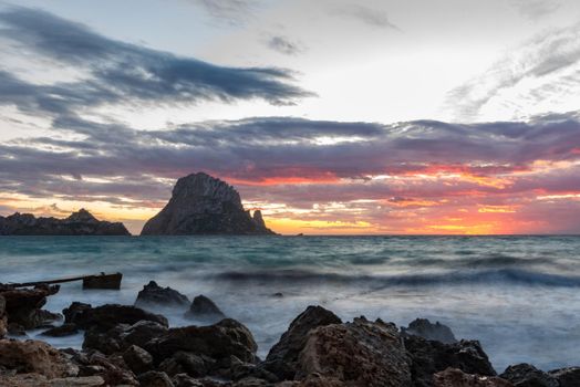 Small wooden pier in Cala d'Hort bay and view of Es Vedra island, Ibiza island, Spain