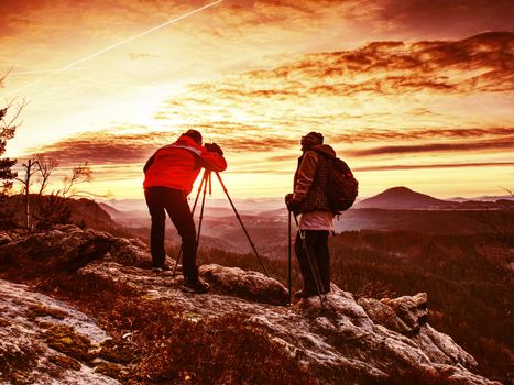 Two wildlife photographers at tripod with set  shinning camera enjoy autumn morning in wildnature