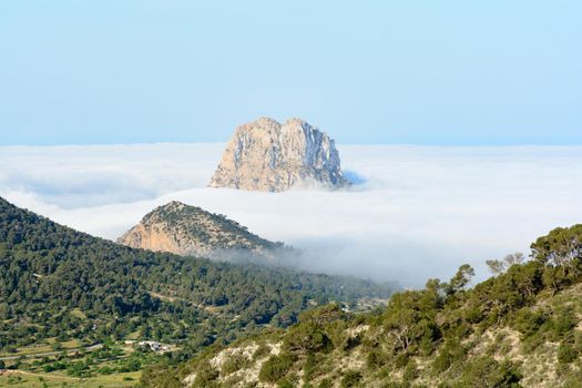 Peak of the mountain is vedra peeping through the fog one autumn morning in Sant Josep de Sa Talaia, Ibiza, Balearic Islands, Spain.