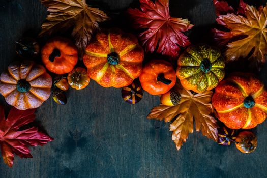 Autumnal flat lay with leaves and pumpkins on wooden background