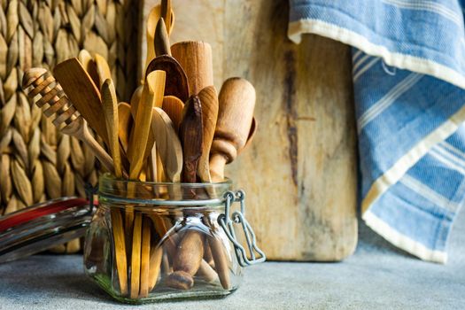 Glass jar with variety of wooden spoons on kitchen table