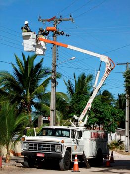 prado, bahia / brazil - december 9, 2009: electricians are seen making repairs to a utility pole in the city of Prado.


