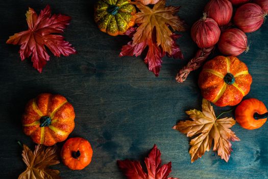 Autumnal flat lay with leaves and pumpkins on wooden background