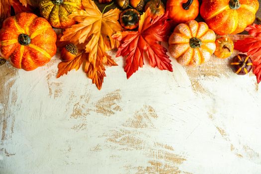 Autumnal flat lay with leaves and pumpkins on wooden background