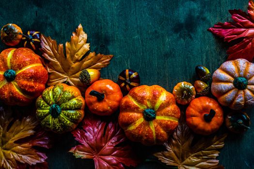 Autumnal flat lay with leaves and pumpkins on wooden background