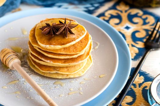 classic american breakfast. homemade banana pancakes on plate sprinkled powder and honey. Pancakes on the kitchen table . Pancake slide with honey topping, decorated with anise seeds