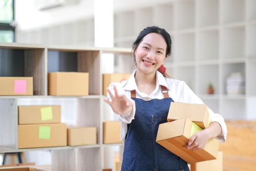 Portrait of Asian young woman working with a box at home the workplace.start-up small business owner, small business entrepreneur SME or freelance business online and delivery concept..