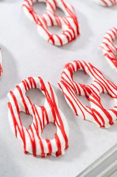 Drizzling melted chocolate over chocolate-dipped pretzels twists.