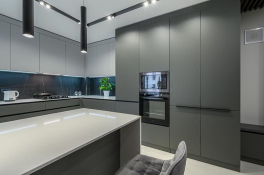 Elegant white and grey luxury kitchen, dining room with kitchen bar and stools in studio apartment interior