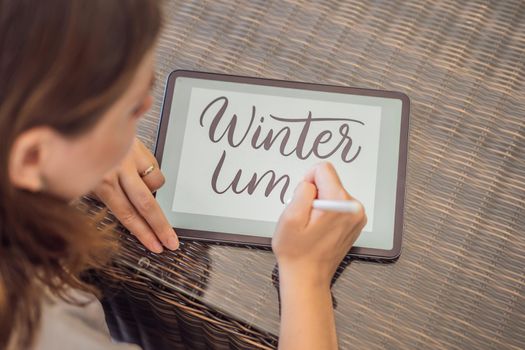 Calligrapher Young Woman writes phrase on digital tablet. Inscribing ornamental decorated letters. Calligraphy, graphic design, lettering, handwriting, creation.
