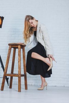 Young woman with pain in her legs after wearing high heels, close up. A woman in a black dress and jacket.