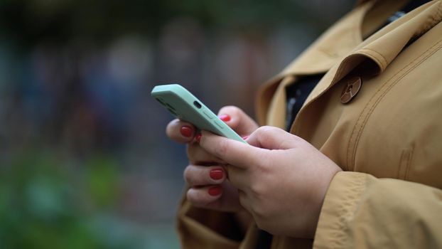 Woman with smartphone, hands holding phone, lady in autumn with gadget outdoors.